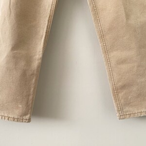 Puede incluir: Un pantal&oacute;n beige de pierna recta y dobladillo ligeramente deshilachado.