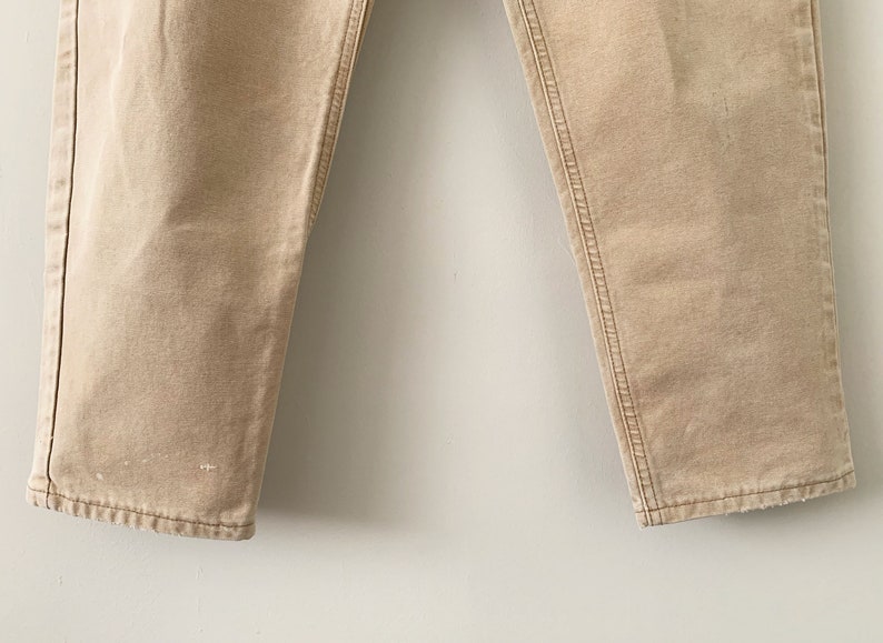 Puede incluir: Un pantal&oacute;n beige de pierna recta y dobladillo ligeramente deshilachado.