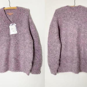 May include: A soft, fuzzy, lavender-colored v-neck sweater with long sleeves. The sweater has a tag that says "Reformation" on it.