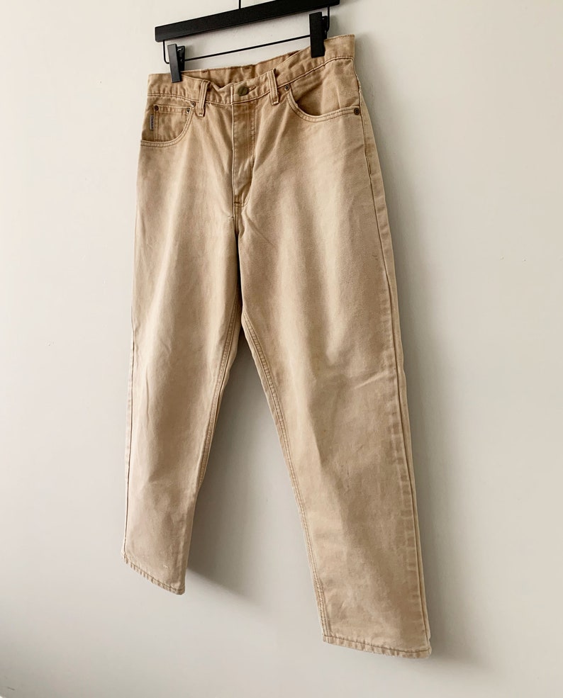 Puede incluir: Un par de pantalones vaqueros de color marr&oacute;n claro, de pierna recta, con cierre de bot&oacute;n y cinco bolsillos.