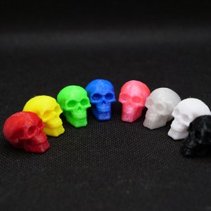 May include: A set of eight miniature skull figurines in various colours, including red, yellow, green, blue, pink, white and black.