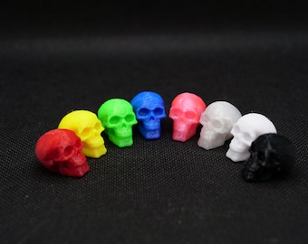 Può includere: Un set di otto figurine di teschio in miniatura di vari colori, tra cui rosso, giallo, verde, blu, rosa, bianco e nero.