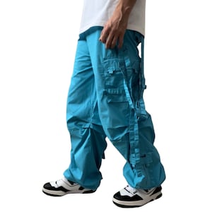 May include: A pair of turquoise cargo pants with multiple straps and pockets. The pants are loose fitting and have a casual style.