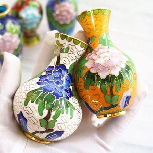 Puede incluir: Cuatro pequeños jarrones de porcelana pintados a mano con diseños florales. Los jarrones son en tonos de azul, amarillo, blanco, verde y rosa.