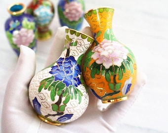 May include: Four small, hand-painted porcelain vases with floral designs. The vases are in shades of blue, yellow, white, green, and pink.