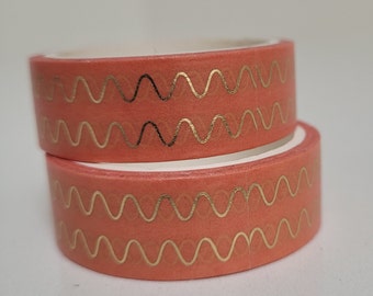 May include: Two rolls of washi tape with a coral pink background and a gold wavy pattern.