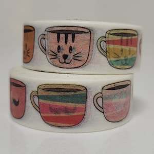 May include: Two rolls of decorative washi tape featuring colorful coffee cup designs. The cups have various patterns and colors, including a cat face, stripes, and solid colors. The tape is white with the cup illustrations printed on it.
