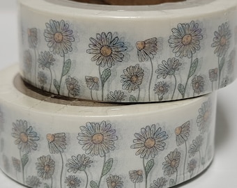 Può includere: Due rotoli di nastro adesivo decorativo washi con un motivo floreale a margherita. Il nastro ha uno sfondo bianco con un motivo ripetuto di margherite nei toni del giallo, arancione e viola, con foglie e steli verdi.