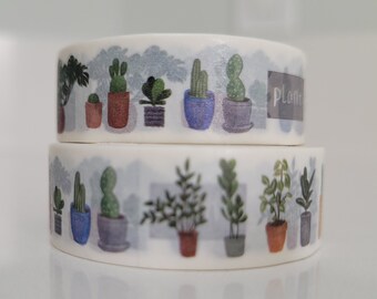 May include: Two rolls of washi tape with a plant theme. The top roll has a light blue background with green plants in pots. The bottom roll has a white background with green plants in pots. The text "Plants" is printed on the top roll.