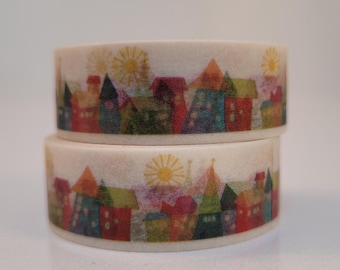 May include: Two rolls of washi tape with a colorful cityscape design. The tape features a repeating pattern of houses with different colors and styles, including red, green, blue, and yellow. The tape is on a white background.