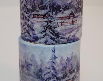 May include: Two rolls of washi tape stacked on top of each other. Each roll features a winter landscape design with snow-covered trees, houses, and a fence, all in shades of blue and purple.