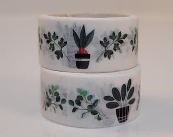 May include: Two rolls of white washi tape with a green and black plant design. The tape has a watercolor effect.
