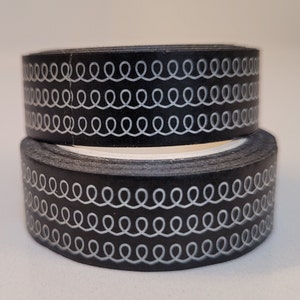 May include: Two rolls of black washi tape with a white repeating pattern of wavy lines.