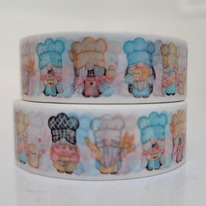 May include: Two rolls of white adhesive tape featuring a repeating pattern of cartoon gnomes dressed as bakers. The gnomes wear blue, tan, and black checkered chef hats and aprons, holding various baked goods like bread, cookies, and small cakes.