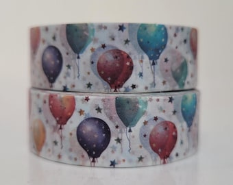 Puede incluir: Dos rollos de cinta adhesiva decorativa apilados verticalmente, con un patrón repetitivo de globos coloridos en tonos azul, morado, rojo y amarillo, intercalados con pequeñas formas de estrellas doradas y oscuras sobre un fondo claro.