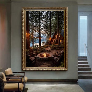 May include: A framed landscape painting depicts a cozy outdoor scene. A stone fire pit with a burning fire is surrounded by wooden chairs. A cabin with string lights is nestled among tall trees, with a lake in the background. The frame is gold.