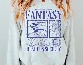 Op de afbeelding: Grijs sweatshirt met een blauwe grafische print die "Proud Member of the Fantasy Readers Society" zegt. De grafiek toont een draak, een roos, een boek en een maan.