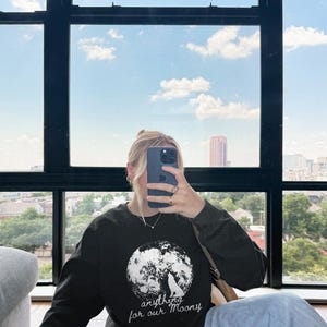 May include: Black sweatshirt with a white wolf howling at the moon graphic. The text "anything for our Moony" is printed below the graphic.