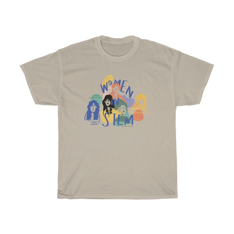 Pu&ograve; includere: Una t-shirt beige chiaro con una grafica blu di donne in STEM. La grafica presenta un gruppo di donne con contorni colorati e il testo "Women in STEM".