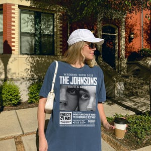 May include: A blue t-shirt with a white print of a wedding tour poster for "The Johnsons, David & Anna". The poster features a black and white photo of a couple's eyes and includes the date "24 May" and the location "Park City".