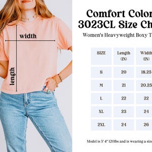 May include: A peach-colored Comfort Colors 3023CL heavyweight boxy t-shirt. The image includes a size chart with measurements in inches for sizes S to 2XL. The model is 5' 4" and 120lbs, wearing a size M.
