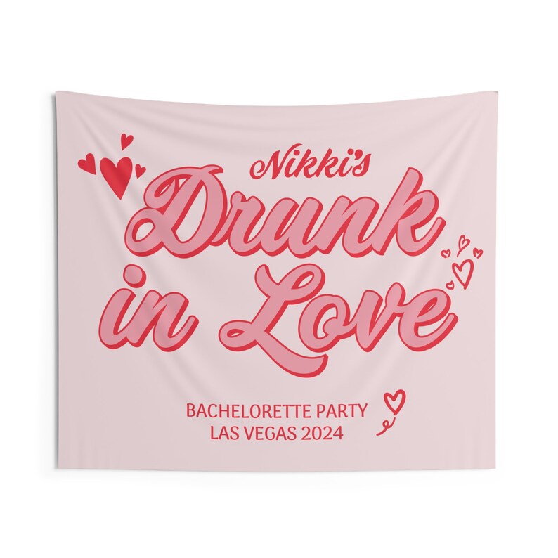 May include: Pink bachelorette party tapestry with the text "Nikki's Drunk in Love" in red and pink lettering. The text "Bachelorette Party Las Vegas 2024" is also included in smaller red lettering.