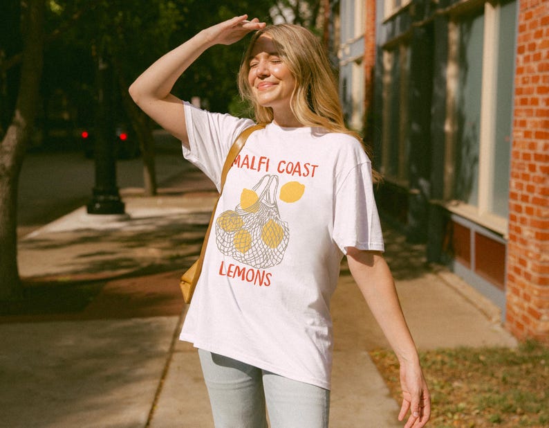 May include: A white t-shirt with a graphic of lemons in a mesh bag and the text "Malfi Coast Lemons".