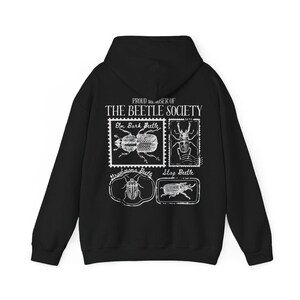 K&ouml;nnte beinhalten: Schwarzer Kapuzenpullover mit einem wei&szlig;en Grafikdruck von vier verschiedenen K&auml;ferarten mit dem Text "PROUD MEMBER OF THE BEETLE SOCIETY" auf der R&uuml;ckseite.