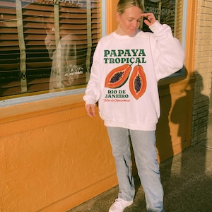 Puede incluir: Sudadera blanca con un gr&aacute;fico de papaya y el texto "Papaya Tropical Rio de Janeiro Feira de Copacabana".