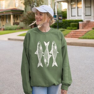May include: A green sweatshirt with a white graphic of three fish. The fish are stylized and have a geometric pattern.