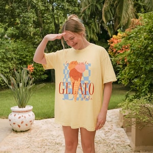 K&ouml;nnte beinhalten: Eine Frau tr&auml;gt ein gelbes T-Shirt mit einem Aufdruck eines Eisbechers und dem Text "La dolce vita Gelato Italia".