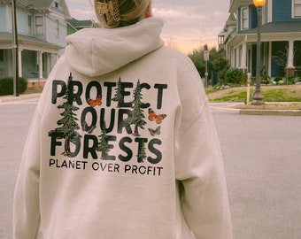May include: A beige hoodie with a graphic print of trees and butterflies. The text on the hoodie reads "Protect Our Forests Planet Over Profit".