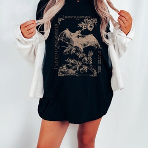 May include: Black t-shirt with a graphic print of a bat and pomegranates. The text "I wanted darkness. I wanted him." is printed on the shirt.
