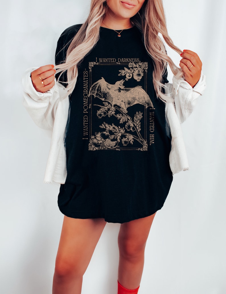 May include: Black t-shirt with a graphic print of a bat and pomegranates. The text "I wanted darkness. I wanted him." is printed on the shirt.