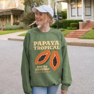 Puede incluir: Sudadera verde con un gr&aacute;fico de papaya y el texto "Papaya Tropical Rio de Janeiro" en una fuente retro.