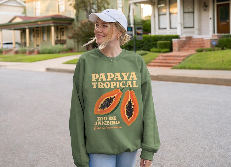 Puede incluir: Sudadera verde con un gr&aacute;fico de papaya y el texto "Papaya Tropical Rio de Janeiro" en una fuente retro.