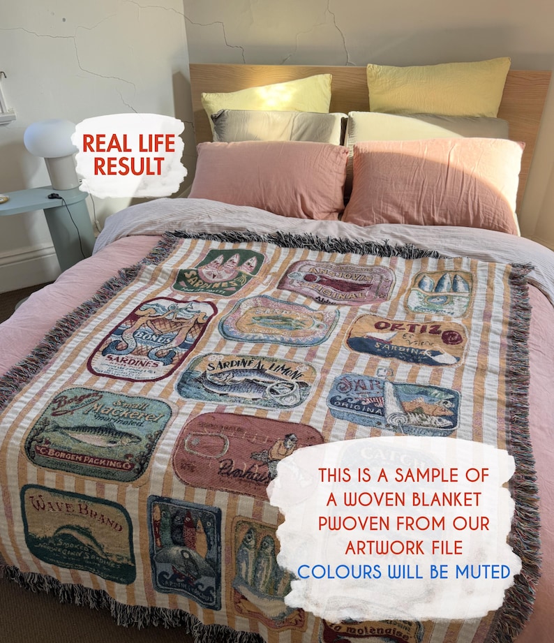 May include: Woven blanket with a sardine can design in various colors, displayed on a bed with pink pillows and a light-colored headboard. The blanket features a striped background and the text "THIS IS A SAMPLE OF A WOVEN BLANKET PWOVEN FROM OUR ARTWORK FILE COLOURS WILL BE MUTED."