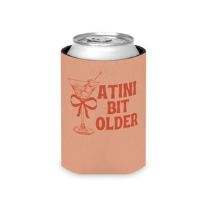 May include: A peach-colored can cooler with a martini glass and the text "A TINI BIT OLDER" in red.