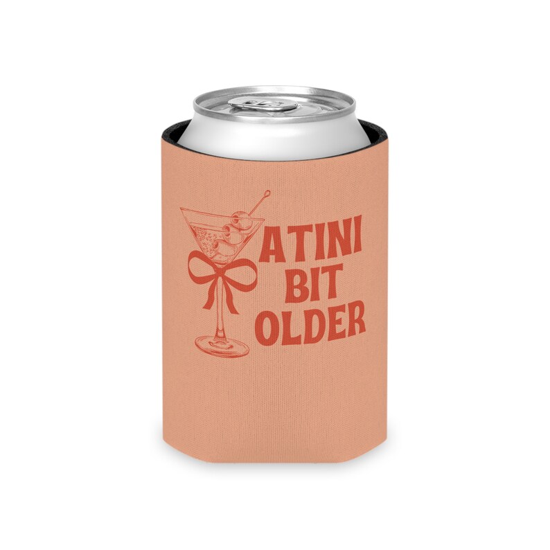 May include: A peach-colored can cooler with a martini glass and the text "A TINI BIT OLDER" in red.