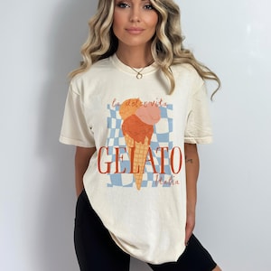 K&ouml;nnte beinhalten: Ein cremefarbenes T-Shirt mit einem Aufdruck eines Eisbechers mit dem Text "la dolce vita GELATO Italia".
