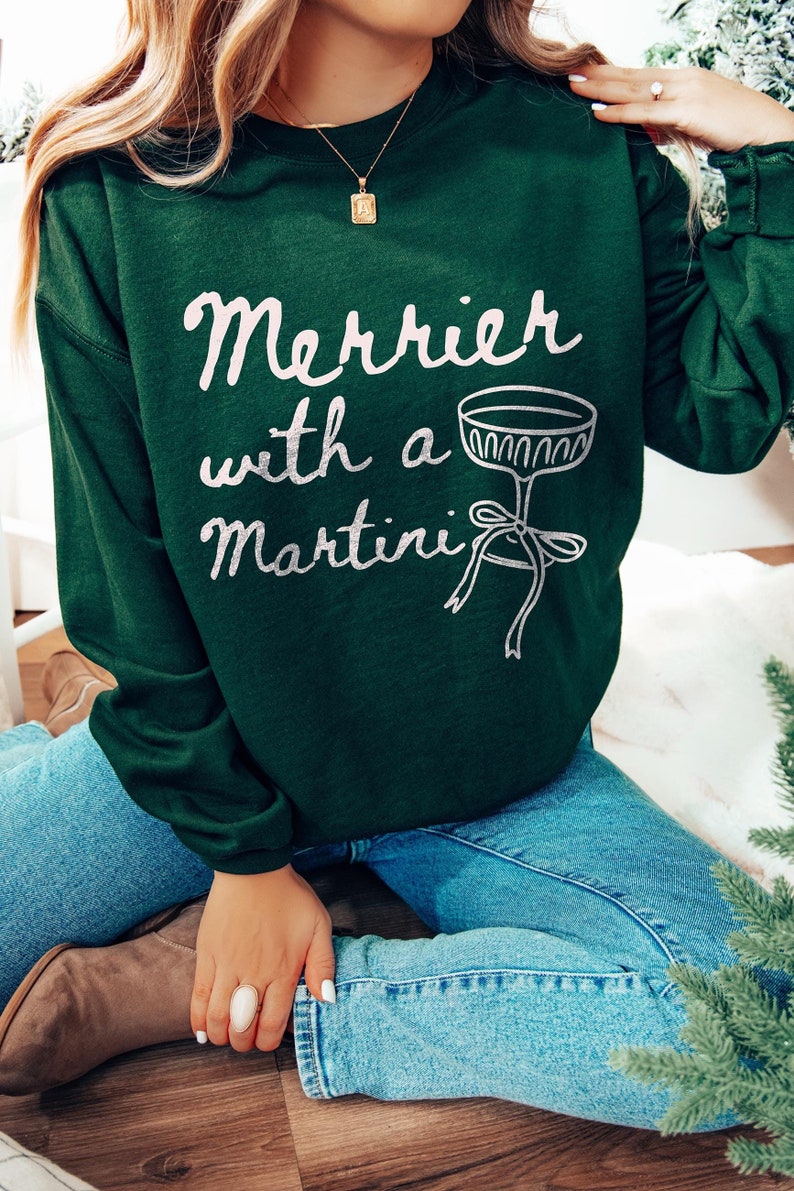 May include: A green sweatshirt with the text "Merrier with a Martini" in white lettering and a silver martini glass graphic.
