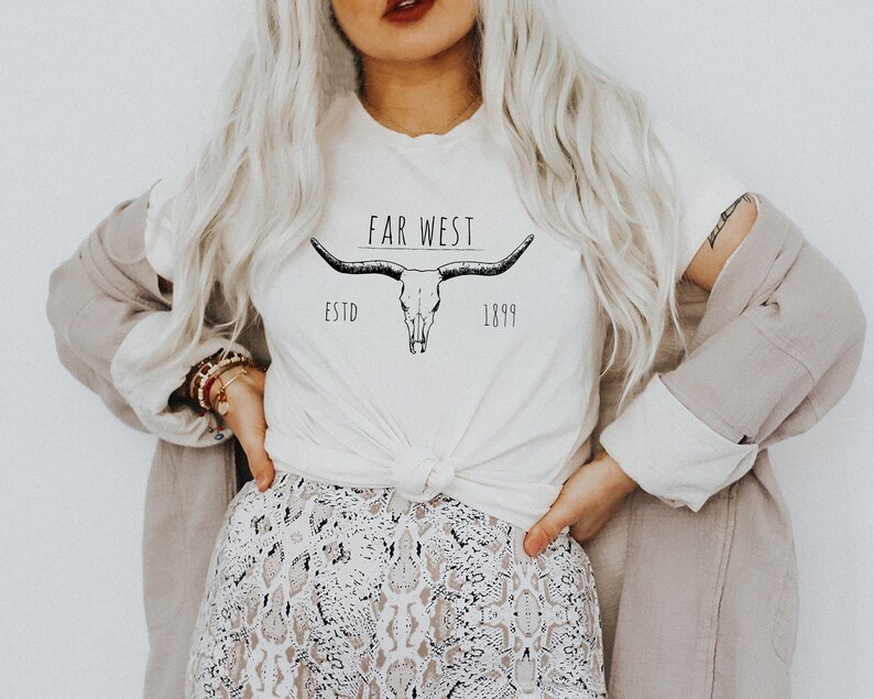 K&ouml;nnte beinhalten: Wei&szlig;es T-Shirt mit einer schwarz-wei&szlig;en Illustration eines Kuhsch&auml;dels mit H&ouml;rnern und dem Text "FAR WEST ESTD 1899".