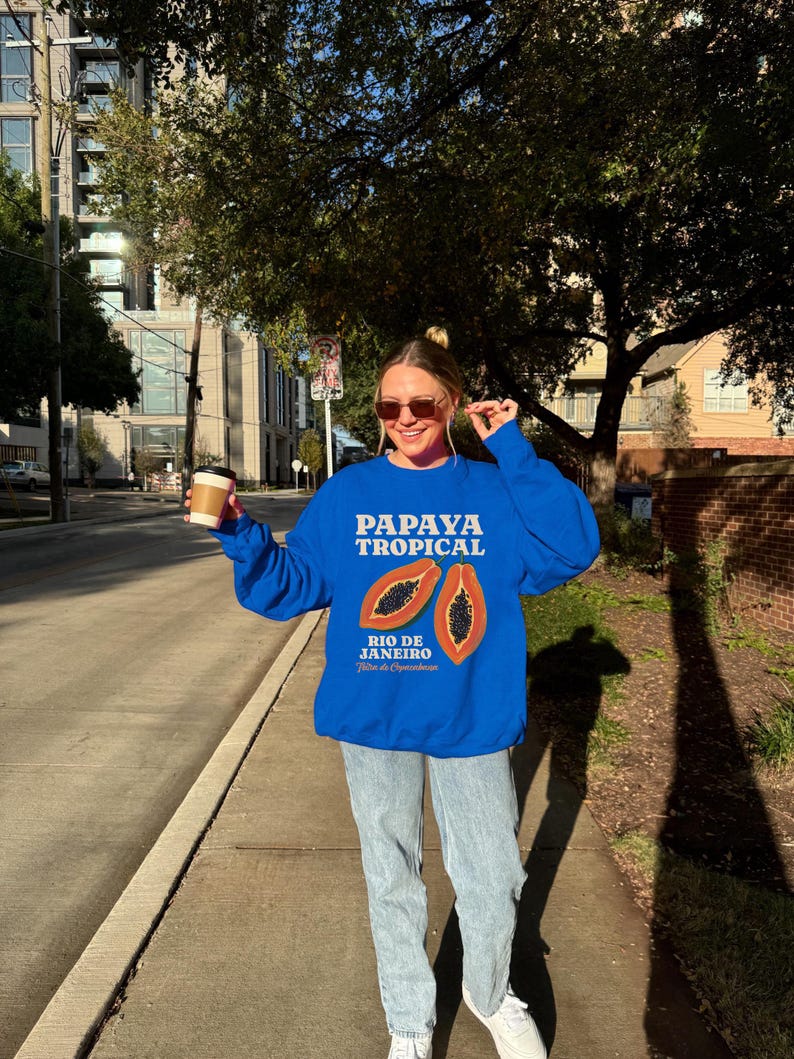 Puede incluir: Una sudadera azul con un gr&aacute;fico de papaya y el texto "Papaya Tropical Rio de Janeiro".