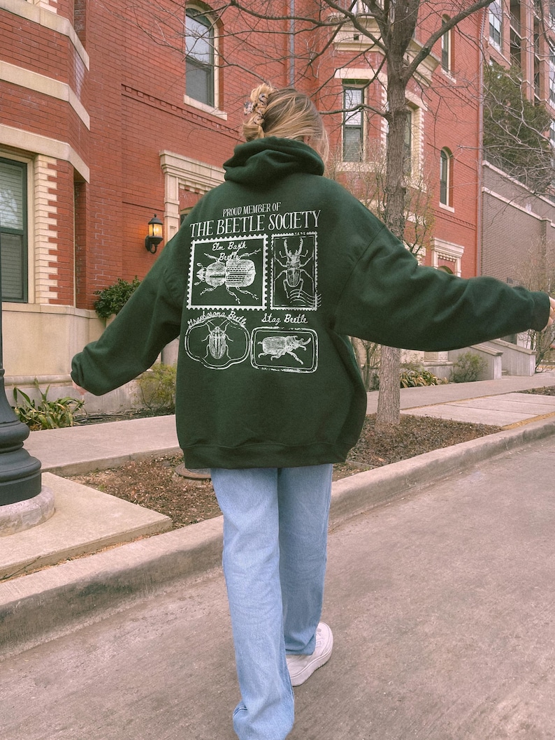 K&ouml;nnte beinhalten: Ein dunkelgr&uuml;ner Hoodie mit einem wei&szlig;en Aufdruck von K&auml;fern und dem Text "Proud Member of The Beetle Society".