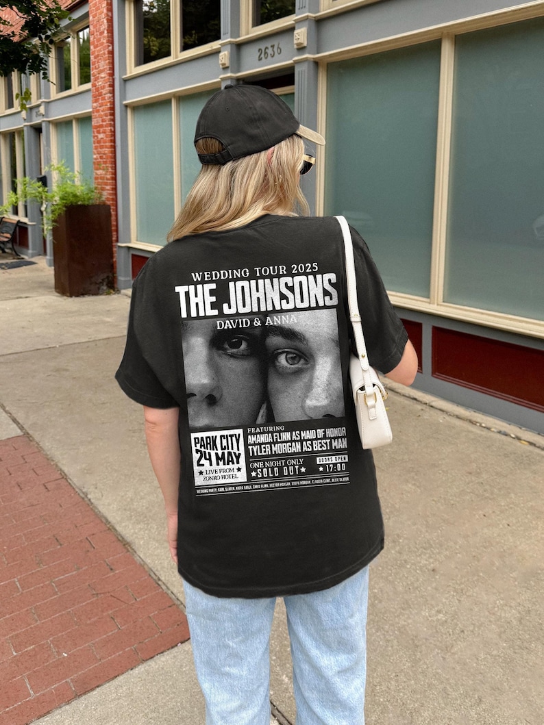 May include: Black t-shirt with a white graphic of a wedding announcement for "The Johnsons, David & Anna" with a photo of the couple's eyes. The announcement includes the date "May 24th" and the location "Park City".