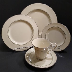 May include: A set of white china dinnerware with a green and silver trim. The set includes a dinner plate, salad plate, bread and butter plate, and a teacup and saucer.