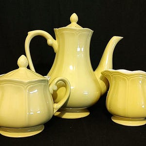 Può includere: Un set da tè in ceramica gialla con teiera, lattiera e zuccheriera. Il set ha un design classico con un corpo scanalato e un manico delicato.