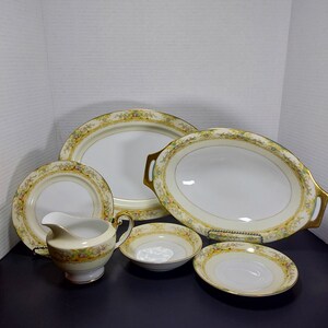Puede incluir: Un juego de seis piezas de vajilla de porcelana vintage de color crema con ribetes dorados y motivos florales. El juego incluye una fuente ovalada grande para servir, una fuente ovalada más pequeña para servir, un plato redondo para cenar, un tazón redondo pequeño, un tazón redondo grande y una jarra para crema.