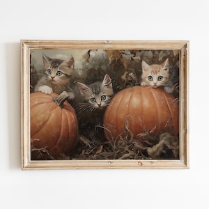 Op de afbeelding: Een vintage schilderij van drie kittens die uit achter pompoenen kijken. De kittens zijn bruin, grijs en wit met groene ogen. De pompoenen zijn oranje en hebben een rustieke, herfstachtige uitstraling.