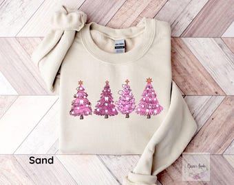 May include: A beige sweatshirt with a pink and white Christmas tree design featuring teeth as ornaments. The text "Sand" is visible at the bottom of the image.